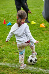 Cute little girl learning to play soccer on a spring day