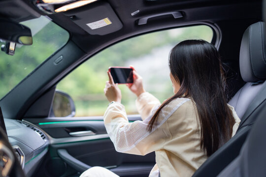 Tourist woman go road trip and sit inside car to take photo on cellphone