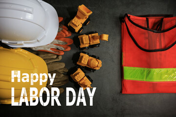 Uniforms for construction workers such as impact helmets, reflective vests, gloves. and machinery Placed on a black background. Happy labor day concept - obrazy, fototapety, plakaty