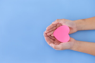 Closeup,Child's hands with a red heart on blue background.Give love philanthropy,help warmth and take care,protect children's health,blood donation and stem cell,valentines day concept.Space for text.