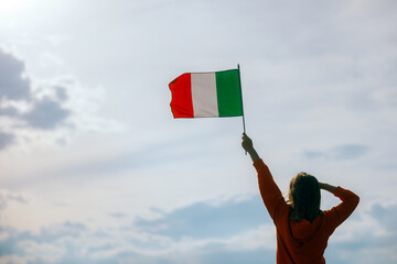 Woman Waving Italian Flag Looking at the Sky. Optimistic girl holding national flag celebrating...