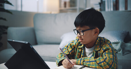 Asian genius boy use tablet doing homework in living room