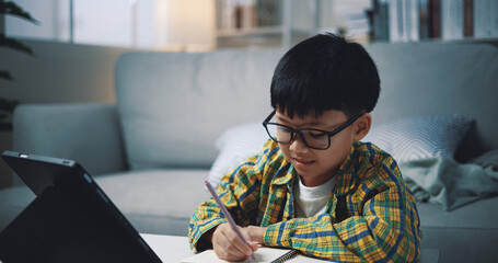 Asian genius boy use tablet doing homework in living room