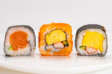 Various homemade japanese style sashimi sushi roll, nori seaweed,  salmon fish, in white ceramic plate isolated on white background.