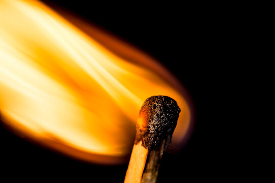 Close up burning matchstick on black background