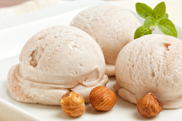 Fototapeta na wymiar Three scoops of handmade hazelnut icecream with nuts on dessert plate