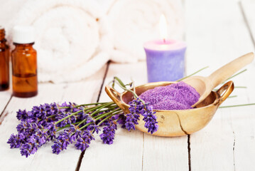 Fototapeta na wymiar lavender flowers, bath salt, massage oil, scented candle and towels on rustic white background, high key image