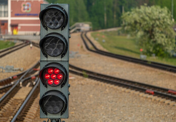 Traffic light at the railway station on the background of rails.