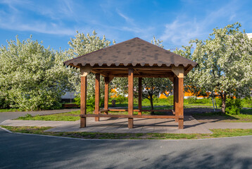 Fototapeta premium Arbor made of wood in the park among flowering trees.
