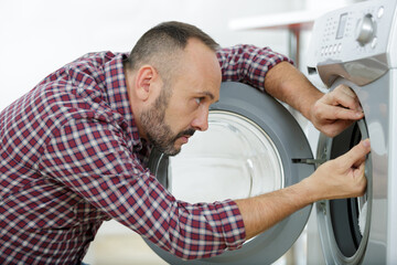 a plumber repairing washing machine - obrazy, fototapety, plakaty
