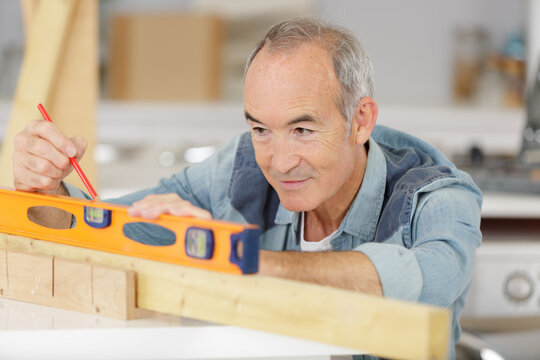 senior constructor holding a ruler on build background