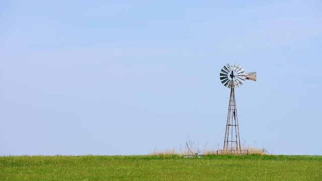 old vintage traditional windmill on grassy prairie horizon