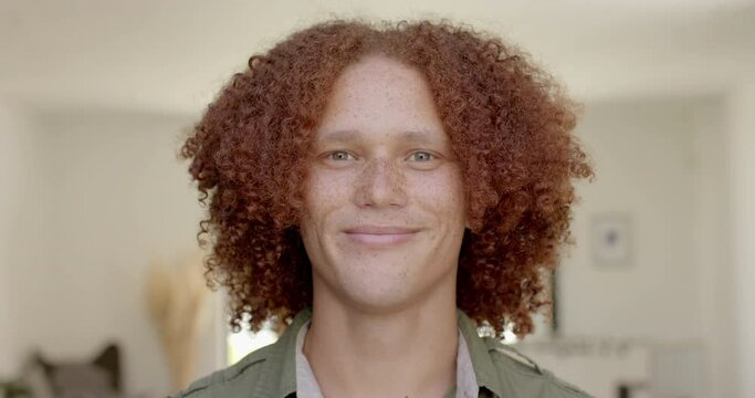 Portrait of happy caucasian man with red hair and freckles smiling at home in slow motion