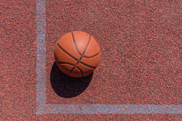 Basketball ball lying on the rubber sport court.Sport red ground outdoor.Top view,Copy space.Basketball banner.