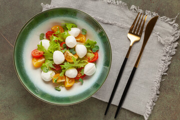 Salad with lettuce, mozzarella and tomatoes in a plate on the table. Caprese salad. Top view