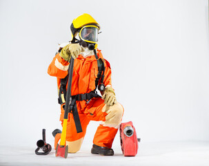 Naklejka premium Professional firefighter is sitting and kneeling down looking sideways and holding an iron axe with one hand while a fire hose is placed on the floor on a white background.