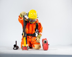 Obraz na płótnie Canvas Professional firefighter is sitting and kneeling down looking down and holding an iron axe with one hand while a fire hose is placed on the floor on a white background.