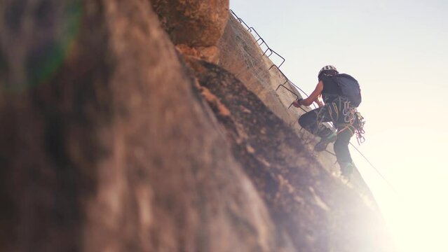 Via ferrata ascension by sportswoman. View of mountaineers climbing