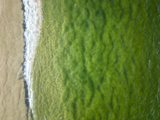 Beautiful aerial top down view to green ocean water and sand