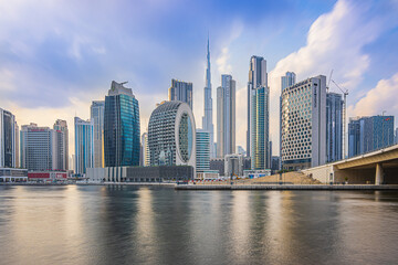 Fototapeta na wymiar Dubai with skyscrapers and Burj Khalifa in the evening. Skyline with a cloudy sky in the evening mood. Waterfront in Dubai Harbour. Houses with glass front and concrete facades architecture