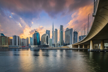 Dubai skyline. Evening mood of the Arabic city. Sunset with skyscrapers in the Emirates overlooking Burj Khalifa. Glazed facade of skyscrapers. Bridge course road from the business center