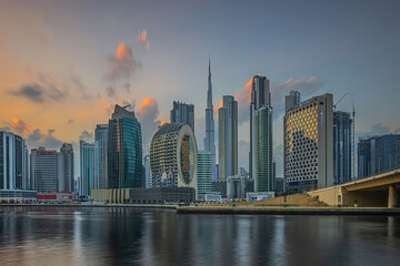Fototapeta na wymiar Sunset in Dubai. Evening sun with clouds over city skyline of United Arab Emirates. City center with skyscrapers of business and office buildings in the evening at sunset