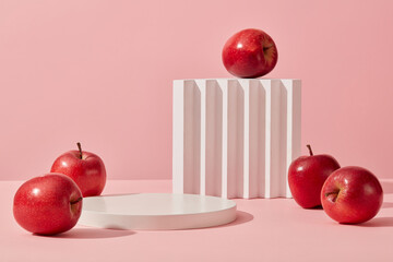 Some red apples displayed on a pink background with cylinder white podiums. Abstract background...