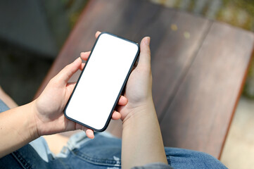 A young girl using her smartphone while chilling on a bench in a public park.