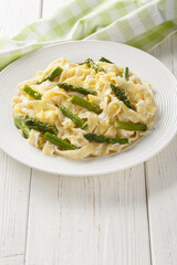 Lemony Asparagus Pasta fettuccine with parmesan cream sauce closeup on the plate on the wooden table. Vertical