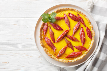 Delicious rhubarb pie with custard closeup on the plate on the wooden table. Horizontal top view from above