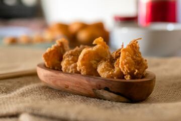 Crispy prawns served on a wooden plate in a traditional kitchen composition