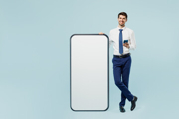 Full body young employee IT business man corporate lawyer wear classic formal shirt tie work in office big huge blank screen mobile cell phone smartphone with area isolated on plain blue background.