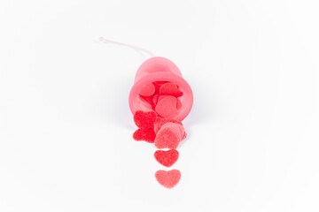 Pink menstrual cup full of small red hearts simulating bleed on a white background. Alternative feminine intimate hygiene product. Women's health, period pain and bleeding concept. Copy space.