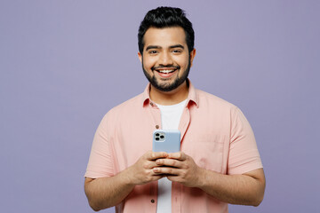 Young smiling happy Indian man he wear pink shirt white t-shirt casual clothes hold in hand use...