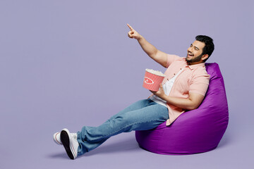 Full body young Indian man he wearing pink shirt white t-shirt casual clothes sit in bag chair...