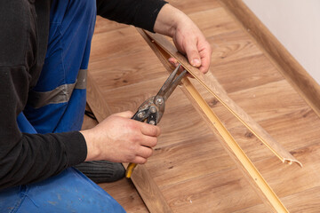 A worker installs a skirting board on the floor in a room