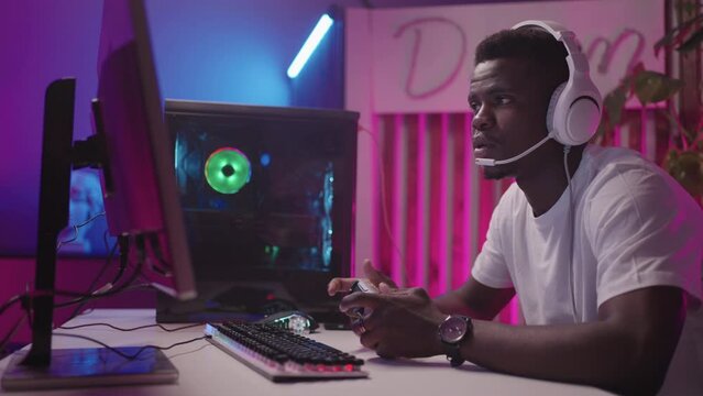 Portrait of a Black Male Engaged in Cyber Entertainment: Playing Video Games and Communicating with Playmates via Joystick and Headset on His PC