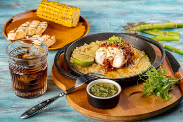 A piece of fish with sauce on a bed of rice or barley, grilled with lime