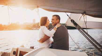 Couple in love on yacht deck while sailing in the sea. Man and beautiful woman having romantic...