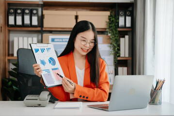 Confident Asian woman with a smile standing holding notepad and tablet at the office.
