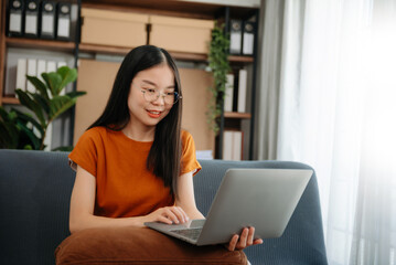 Naklejka premium Asian woman using the smartphone and tablet on the sofa at home.