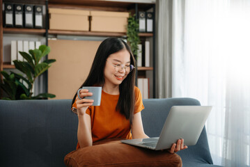 Asian woman using the smartphone and tablet on the sofa at home.