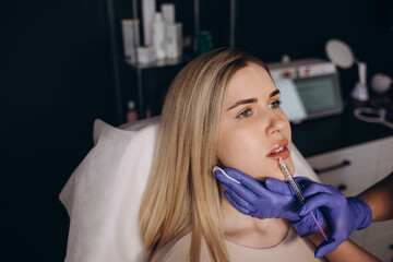 Smile lifting and lip augmentation. Beautician doctor hands doing beauty procedure to female face...