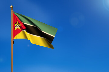 Mozambique. Flag blown by the wind with blue sky in the background.