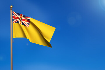 Niue. Flag blown by the wind with blue sky in the background.