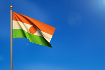 Niger. Flag blown by the wind with blue sky in the background.