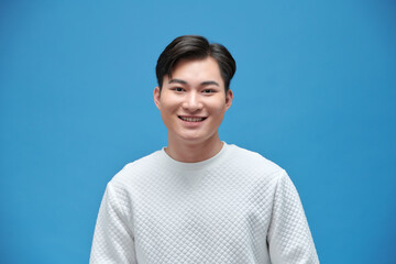 Fototapeta premium Portrait of good looking asian man over blue background.