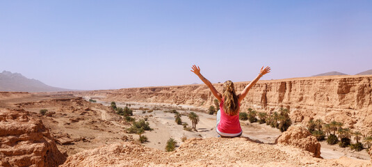 Woman with arms raised, cliff and canyon- Morocco