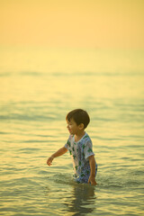 Asian boy playing on a sandy beach near the sea.