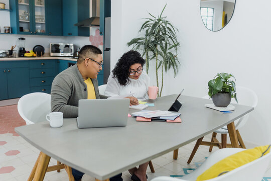 Latin lesbian couple working and using laptop together at home in Mexico, Hispanic homosexual people from lgbt community in Latin America